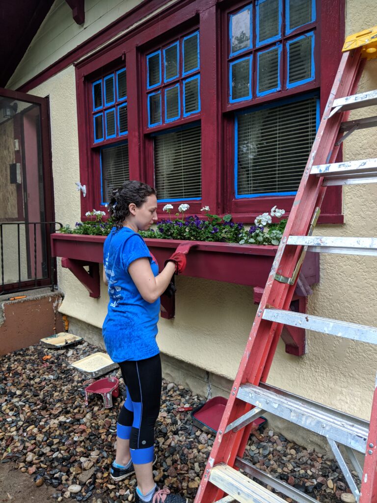 A volunteer adds masking tape to borders for painting