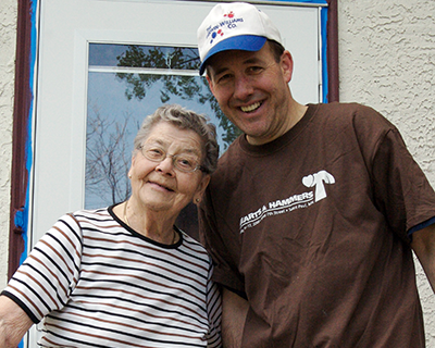 A volunteer posing while smiling with a homeowner