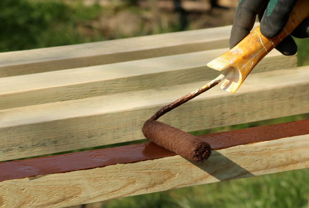 A paint roller staining planks of wood