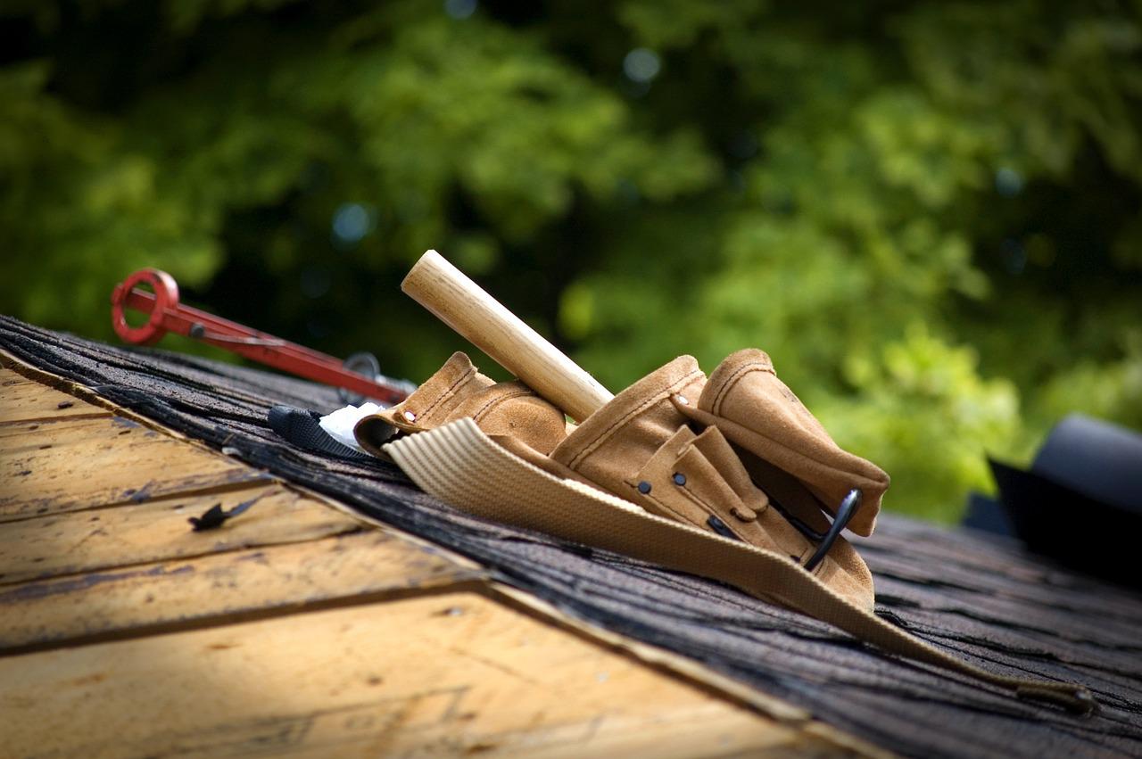A tool belt resting on a roof during a shingle installation