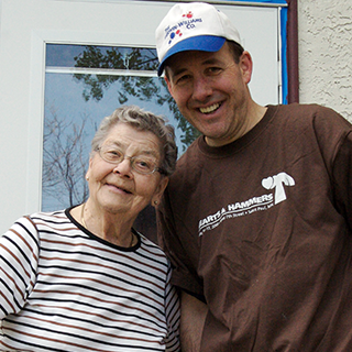 A volunteer posing while smiling with a homeowner